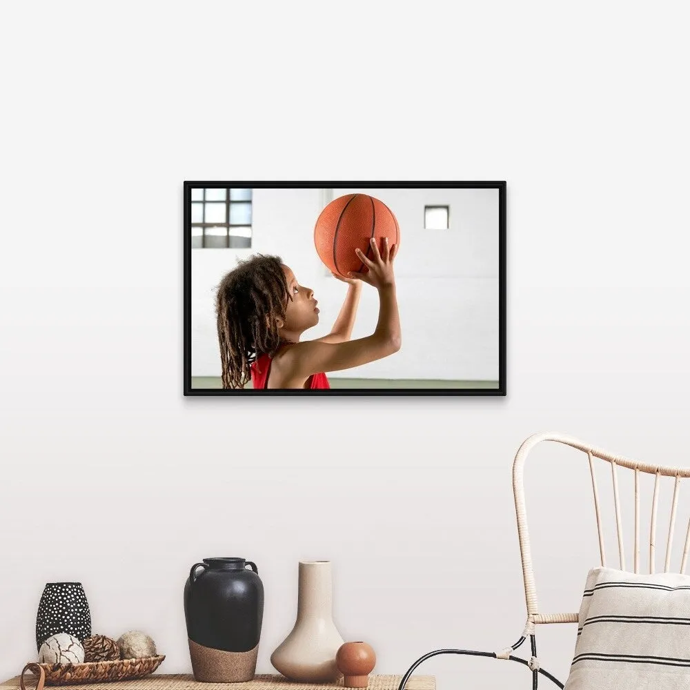 "Boy aiming a shot with a basketball in a school sports hall." Black Float Frame Canvas Art