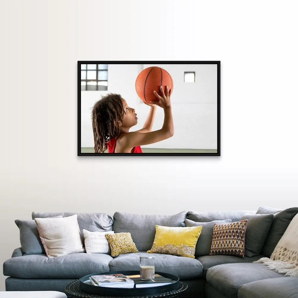 "Boy aiming a shot with a basketball in a school sports hall." Black Float Frame Canvas Art